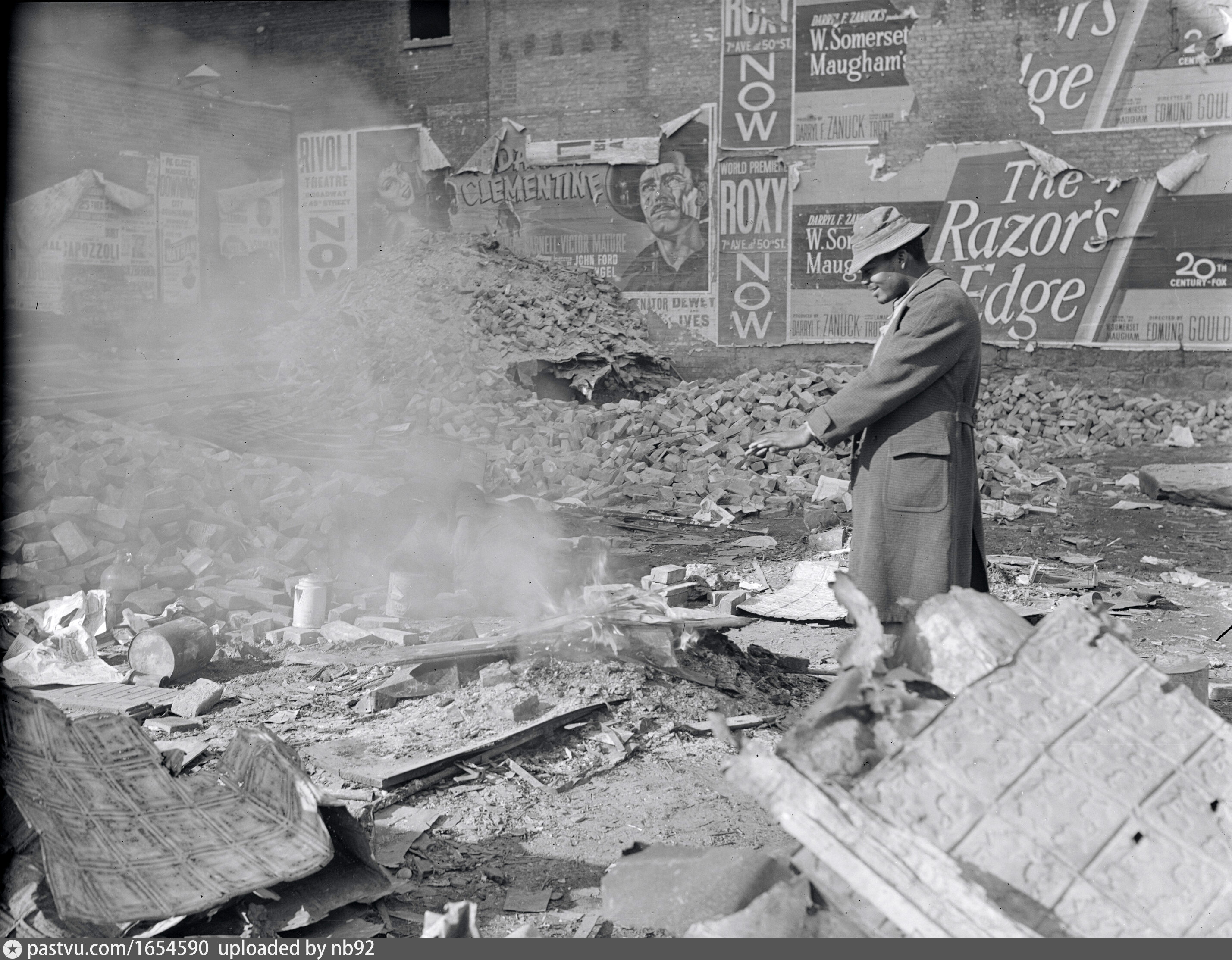 Man warming himself by a fire in a derelict lot