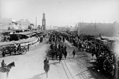 Troupe traversant les Bd de Casablanca, au fond la tour de la porte Bab-es-Souck [i.e. tour de l'horloge] (1913)