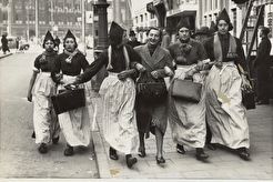 Op de eerste dag van de oorlog lopen geëvacueerde Volendamse meisjes over het Damrak (1940)